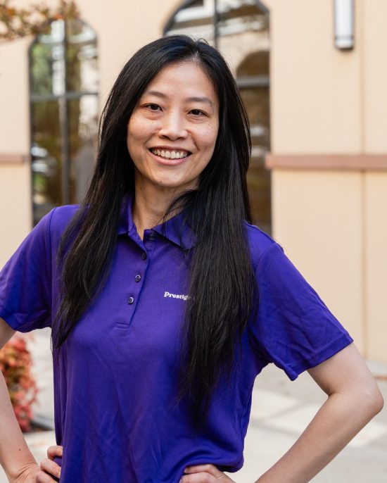 A woman in purple shirt standing next to building.