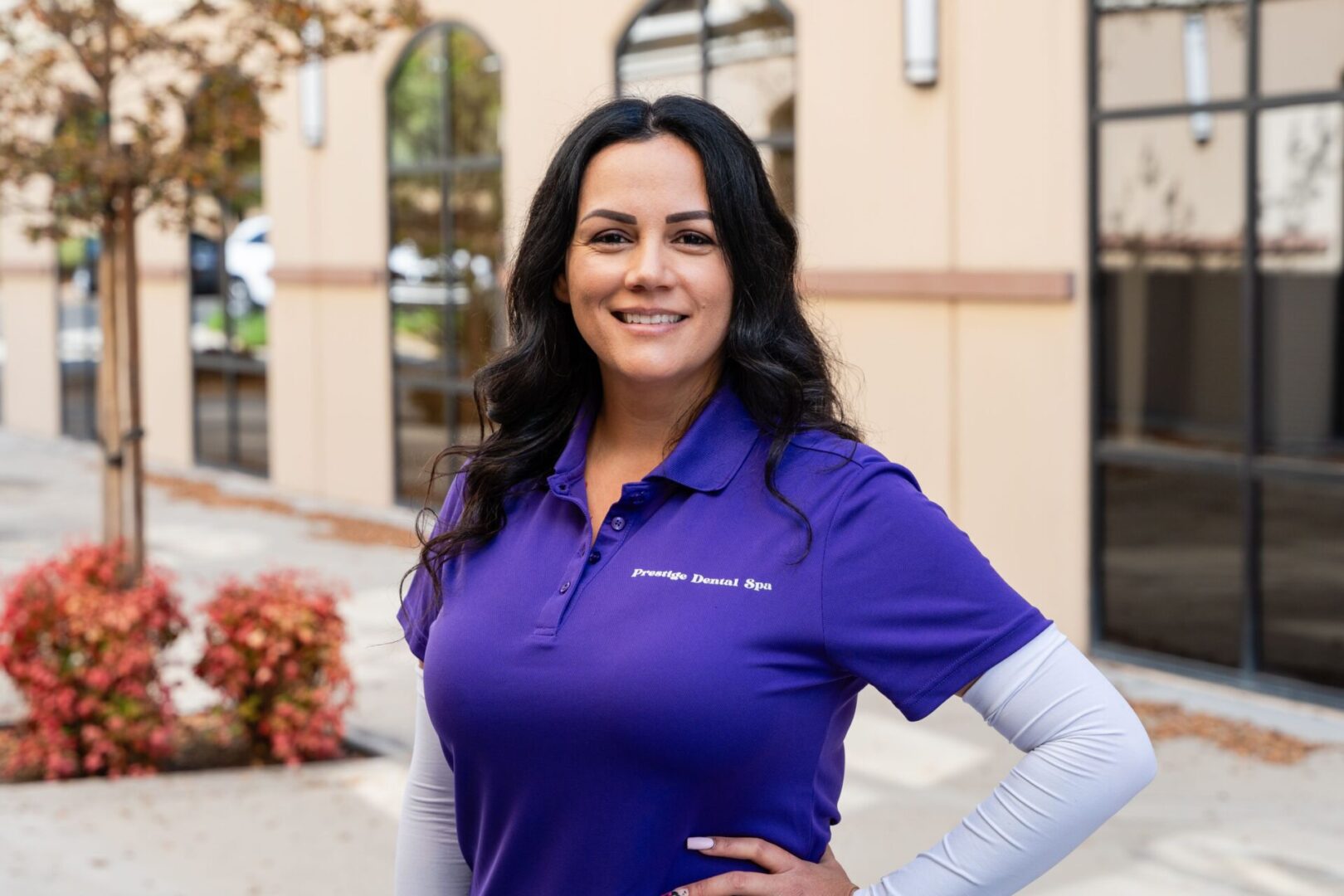 A woman in purple shirt standing next to building.