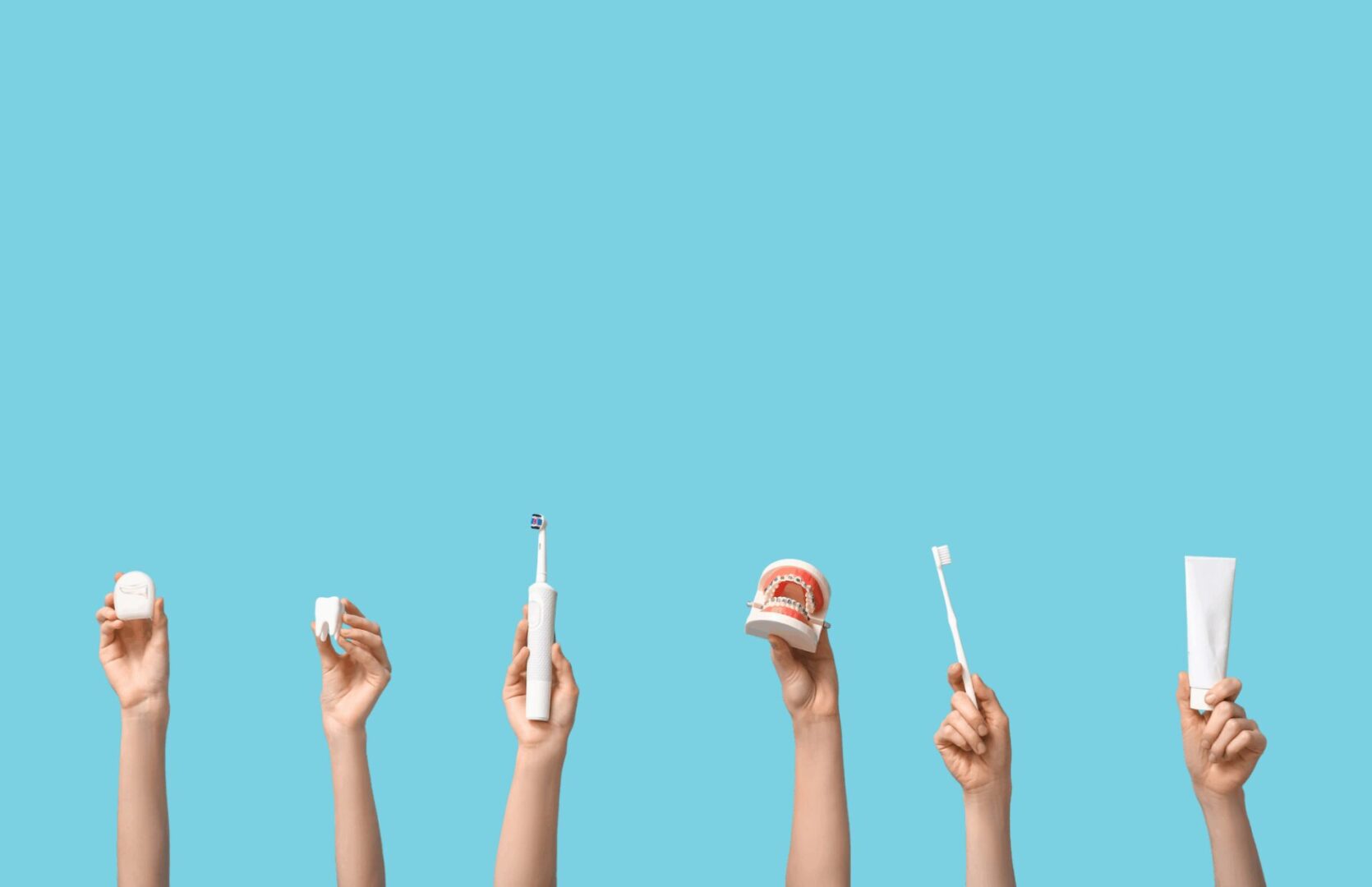 Hands holding dental care items on a blue background, representing preventive dentistry and dentures at Prestige Dental Spa in Lake Elsinore.