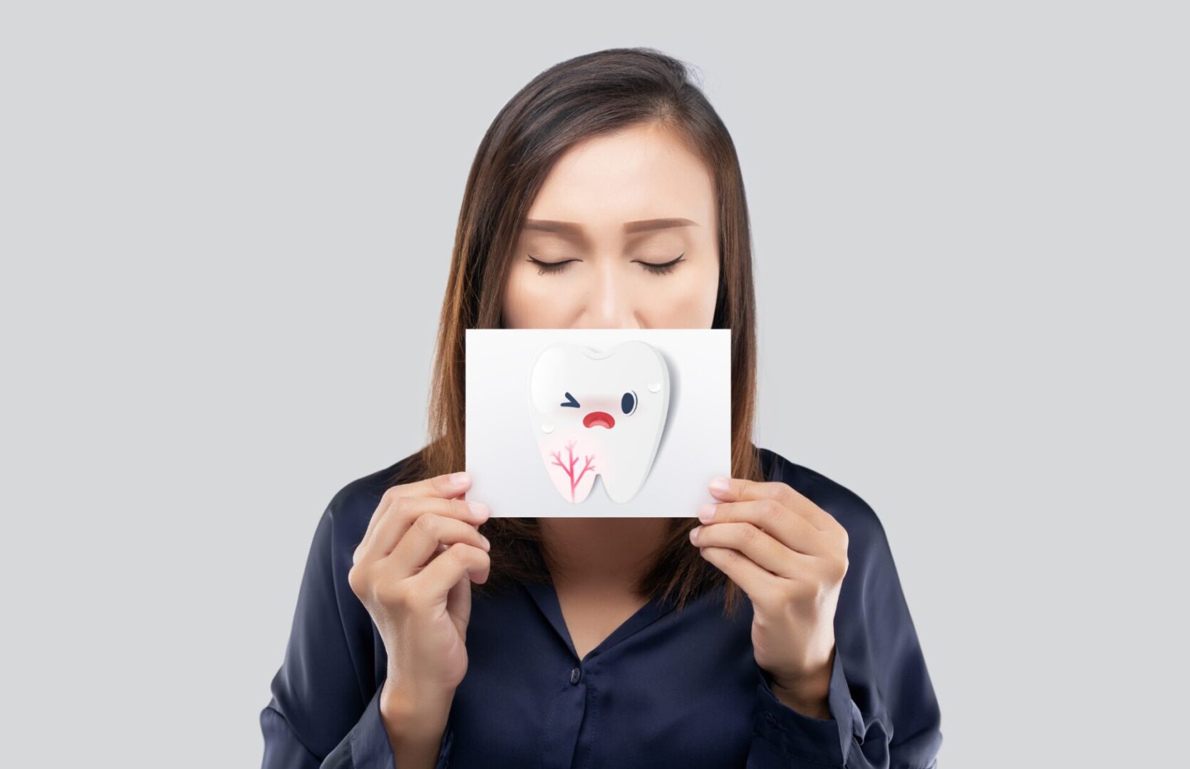 image of a woman holding a drawing of an aching tooth in a piece of paper